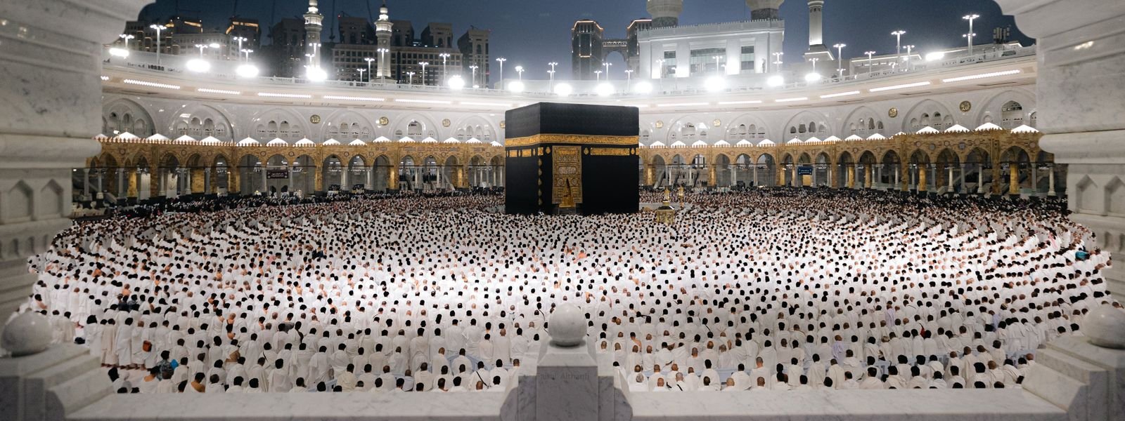 Kaaba at night surrounded by rows of worshippers in Masjid al-Haram